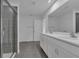 Elegant bathroom featuring double sinks, large mirror, tiled shower and modern fixtures at 9153 Harris Hawk Dr, Leesburg, FL 34788