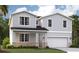 Charming two-story home featuring shaker siding and a welcoming front porch, with stone accents and a two car garage at 9153 Harris Hawk Dr, Leesburg, FL 34788