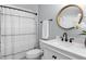 Well-lit bathroom with a shower/tub combo, a white vanity, and a round decorative mirror at 11005 Cypress Leaf Dr, Orlando, FL 32825