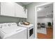 Laundry room featuring white washer and dryer units with overhead cabinets, located next to a bonus room at 11005 Cypress Leaf Dr, Orlando, FL 32825