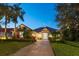 Charming one-story home with a well-manicured lawn, lush landscaping, and a brick driveway at twilight at 11139 Camden Park Dr, Windermere, FL 34786