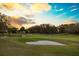 Picturesque golf course view featuring a green, sand traps, and golf cart at sunset at 11139 Camden Park Dr, Windermere, FL 34786