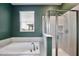 Bathroom featuring soaking tub and glass enclosed shower with green accent wall at 11725 Language Way, Orlando, FL 32832