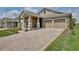 Charming house with brick-paved driveway, two-car garage, stone-accented columns, and manicured lawn at 11725 Language Way, Orlando, FL 32832