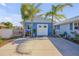 Blue garage with white doors and a concrete driveway lined with palm trees and some landscaping at 120 Sand Dunes Dr, Ormond Beach, FL 32176