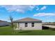 Rear exterior of home showing gray stucco, a compact lawn, and minimalist design elements at 1313 June Lake Loop, Lake Hamilton, FL 33851
