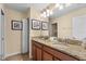 Bathroom with a double sink, granite countertops, and framed artwork on the walls at 1405 Thunderbird Rd, Davenport, FL 33896
