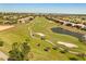 Aerial view of a verdant golf course with bunkers and a lake, surrounded by homes in a golf community at 1405 Thunderbird Rd, Davenport, FL 33896
