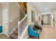 Hallway with staircase, showing neutral wall colors and bright tile floors, plus an accent chair at 1405 Thunderbird Rd, Davenport, FL 33896