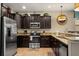 Modern kitchen featuring granite countertops, dark wood cabinets, and stainless steel appliances at 1405 Thunderbird Rd, Davenport, FL 33896