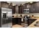 Well-equipped kitchen featuring dark wood cabinets, stainless steel appliances, and granite countertops at 1405 Thunderbird Rd, Davenport, FL 33896