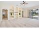 Living room with neutral carpet, built-in shelving, ceiling fan, and sliding glass doors to the outdoor patio at 14313 Roxshire Dr, Orlando, FL 32837