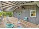 Relaxing covered outdoor deck with wooden floors, gray metal siding, lighting, and comfortable seating at 145 Baywood Dr, Oak Hill, FL 32759