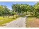 Gravel driveway leading to a home shaded by a mature tree on a sprawling lot with wooden fencing at 145 Baywood Dr, Oak Hill, FL 32759