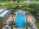 A high angle view of the community pool showcasing the ample seating and palm tree lined walkways at 1539 Corolla Ct, Reunion, FL 34747