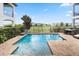 A backyard pool with a sun shelf surrounded by a brick patio overlooks a lush golf course at 1539 Corolla Ct, Reunion, FL 34747
