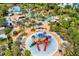 Aerial view of a colorful splash pad with slides and water features, surrounded by palm trees and lounge areas at 1539 Corolla Ct, Reunion, FL 34747