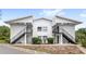 Exterior view of a two-story condo featuring private entrances with stairs and well-maintained landscaping at 1550 11Th Ne St # H-4, Winter Haven, FL 33881