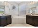 Charming bathroom featuring dual vanities, a large soaking tub, and neutral tile flooring at 16936 Champlain St, Clermont, FL 34714