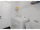Well-lit laundry room featuring a white washer, dryer, utility sink and storage shelves at 16936 Champlain St, Clermont, FL 34714