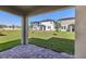 A covered patio with brick pavers overlooks a spacious backyard with lush green grass at 2236 Hen Rd, Minneola, FL 34715