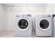Modern laundry room equipped with a washer, dryer, and overhead shelving at 2252 Emerald Springs Dr, Apopka, FL 32712