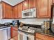 Close-up of stainless steel appliances, dark granite countertops, and wooden cabinetry at 2530 Holtrock St, Kissimmee, FL 34747