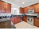 Kitchen area highlighting stainless steel appliances, dark granite counters, and cherry wood cabinets at 2530 Holtrock St, Kissimmee, FL 34747
