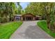 Charming single-story home with a brick facade, a covered porch, and a long driveway surrounded by lush greenery at 25548 Pine Valley Dr, Mount Plymouth, FL 32776