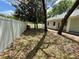 Backyard with a white vinyl fence, shaded by mature trees and lush green grass at 25721 Pinehurst St, Sorrento, FL 32776