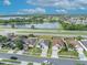 An aerial view highlights the subject home among neighborhood homes near a lake and a busy street at 2607 Quail Pond Way, Kissimmee, FL 34743