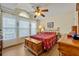 Bright bedroom with hardwood floors, arched window, ceiling fan, and wooden furniture at 2607 Quail Pond Way, Kissimmee, FL 34743