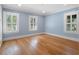 Bright bedroom featuring hardwood floors, soft blue walls, three windows, and white trim at 266 Chase Ave, Winter Park, FL 32789