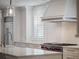 Close up of kitchen with stainless appliances, range hood, white cabinets, and marble countertops at 266 Chase Ave, Winter Park, FL 32789