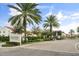 Community entrance with a decorative sign, palm trees, manicured hedges, and a gated entry at 2710 Bolzano Dr, Apopka, FL 32712