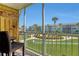 Screened-in balcony with seating overlooks lush lawns and tropical landscaping on a sunny day at 325 N Causeway # D-206, New Smyrna Beach, FL 32169