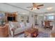 Comfortable living room with sofa, mirrored wall, ceiling fan, adjacent dining area, and TV console at 325 N Causeway # D-206, New Smyrna Beach, FL 32169