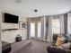 Living room featuring gray sofa, brick accent wall, tv, and french doors leading to the outdoors at 4200 Oaktree Dr, Davenport, FL 33837