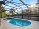 Beautiful screened-in pool with a hot tub, surrounded by lush landscaping for privacy at 4200 Oaktree Dr, Davenport, FL 33837