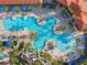 Aerial view of a community pool, with palm trees, lounge chairs, umbrellas, and a water slide feature at 4200 Oaktree Dr, Davenport, FL 33837