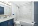 Modern bathroom with tub, shower, sink, and stylish blue vanity with marble walls at 509 Eastwood Ln, Daytona Beach, FL 32118