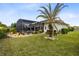 Expansive backyard featuring a screened pool enclosure and a palm tree providing a tropical ambiance at 5509 Meadow Hill Loop, Lady Lake, FL 32159