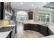 Modern kitchen featuring sleek appliances, wood flooring, dark cabinetry, and white countertops at 5509 Meadow Hill Loop, Lady Lake, FL 32159