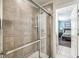 Modern walk-in shower with glass door and light tilework, adjacent to a bedroom at 8808 Macapa Dr, Kissimmee, FL 34747