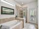 Bright bathroom featuring a soaking tub and frameless glass shower with tile surround at 8808 Macapa Dr, Kissimmee, FL 34747