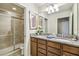 Bathroom featuring double sinks, a granite countertop, wooden cabinets, and a shower with sliding glass doors at 8808 Macapa Dr, Kissimmee, FL 34747