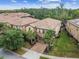 Aerial view of a tan home featuring a two car garage, brick driveway, green lawn and mature landscaping at 8808 Macapa Dr, Kissimmee, FL 34747