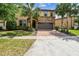 Charming two-story home with a stone facade, a two-car garage, and mature palm trees in the front yard at 8808 Macapa Dr, Kissimmee, FL 34747