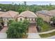 Overhead view of a tan house with a brick driveway and a lush landscaped yard with tropical trees at 8808 Macapa Dr, Kissimmee, FL 34747