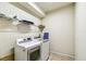 Modern laundry room with white washer and dryer, tiled floor, and built-in shelving at 8808 Macapa Dr, Kissimmee, FL 34747